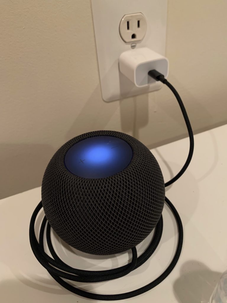 HomePod mini plugged in to a standard U.S. wall power outlet